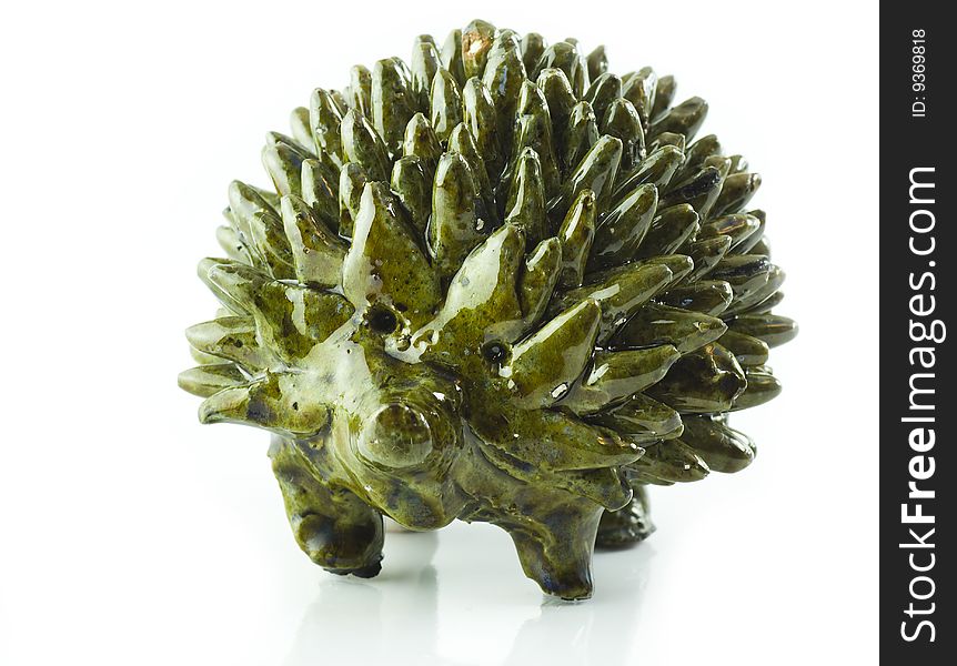 Figurine of ceramic glazed hedgehog isolated on the white background with reflection, it was done by a folk artist 20 years ago