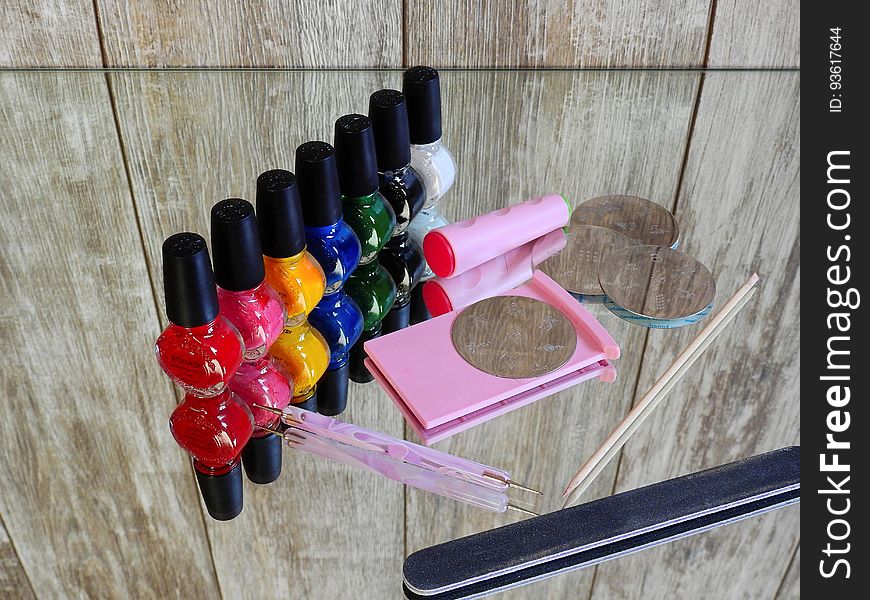 Colorful bottles of nail polish with manicure emery board on mirror. Colorful bottles of nail polish with manicure emery board on mirror.