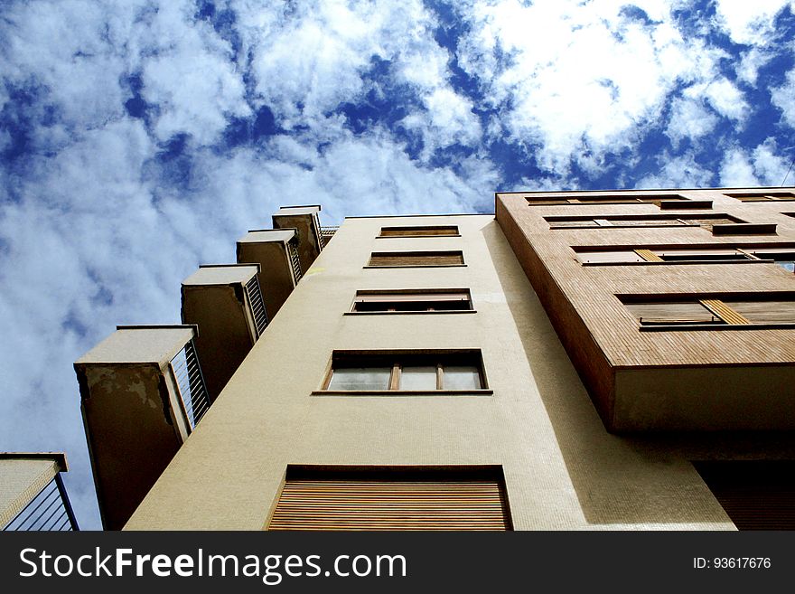 Facade of balconies and windows on apartment building against blue skies.