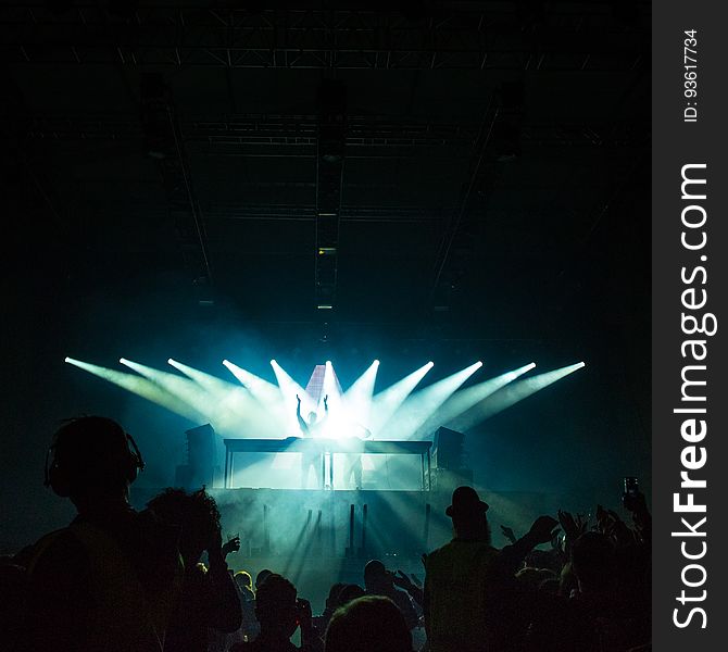 Performer in spotlights on stage during rave or concert in dark stadium. Performer in spotlights on stage during rave or concert in dark stadium.