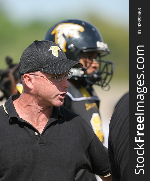 Man in Black Polo Shirt Wearing Black and Yellow Snapback Near Man in Black and Yellow Football Jersey during Daytime