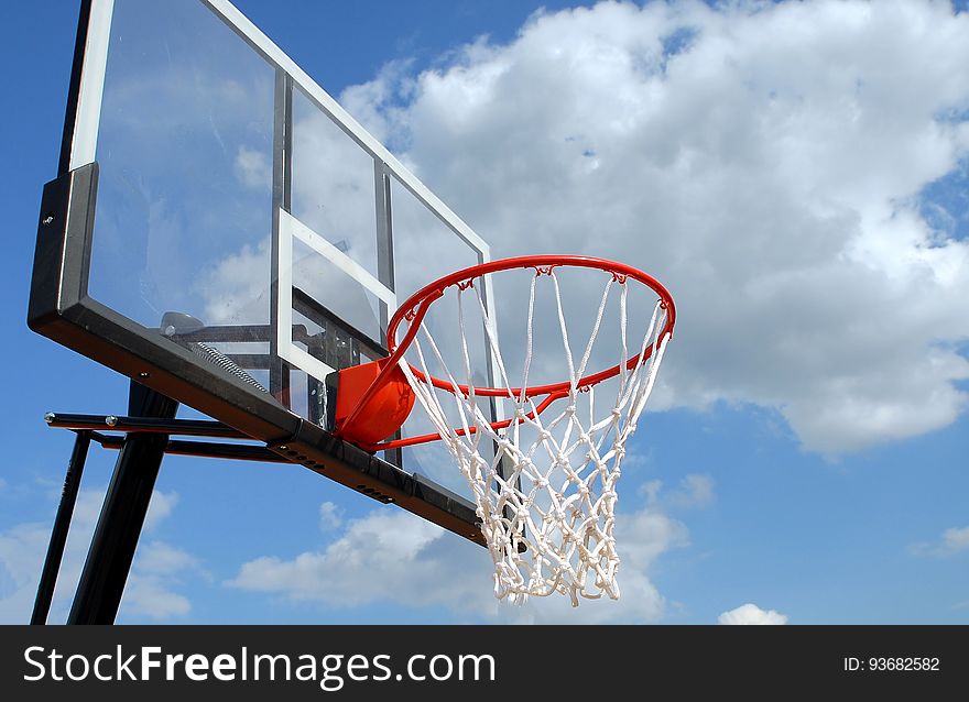 Basketball hoop on painted backboard against blue skies on sunny day. Basketball hoop on painted backboard against blue skies on sunny day.