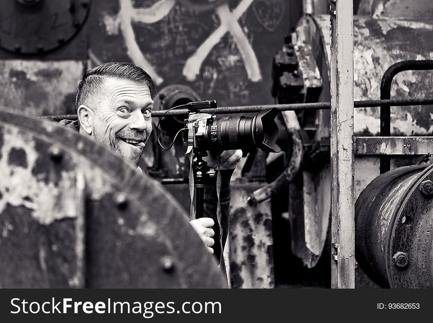 Smiling male photographer surrounded by industrial equipment in black and white. Smiling male photographer surrounded by industrial equipment in black and white.