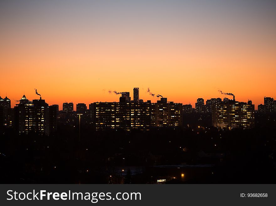 Silhouette of city skyline against orange skies at sunset. Silhouette of city skyline against orange skies at sunset.