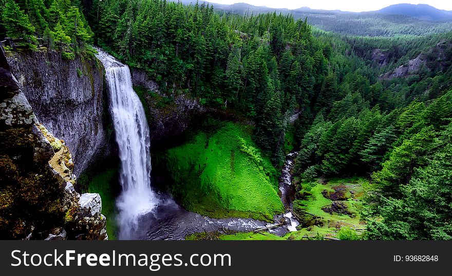Waterfall over steep cliff in green pine forest. Waterfall over steep cliff in green pine forest.