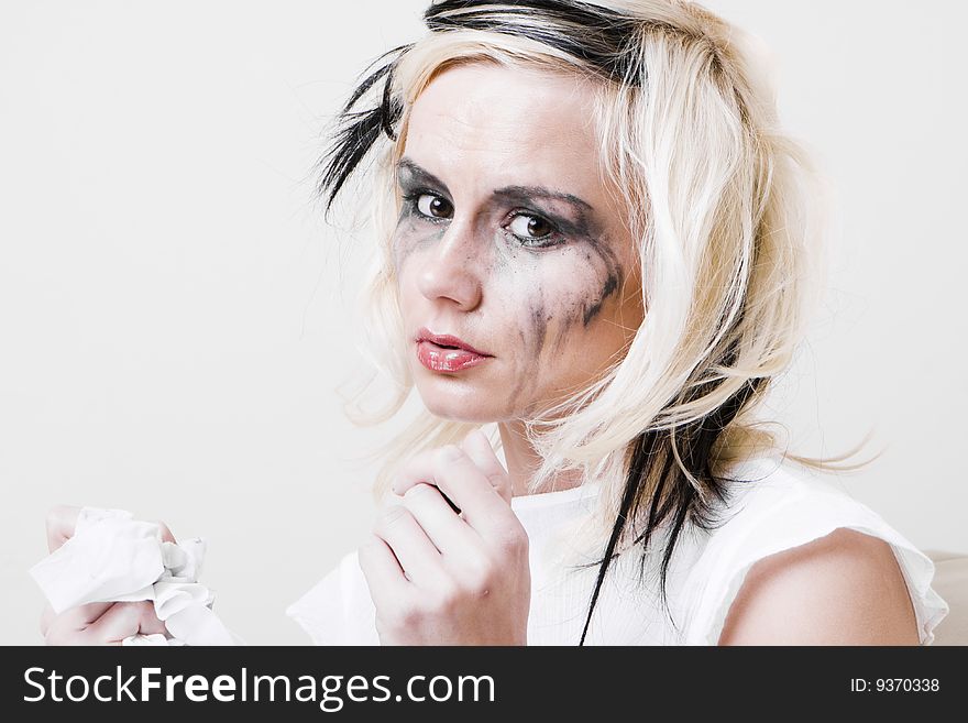 Portrait of blond girl with trendy makeup smudging her face by lipstick crying. Portrait of blond girl with trendy makeup smudging her face by lipstick crying