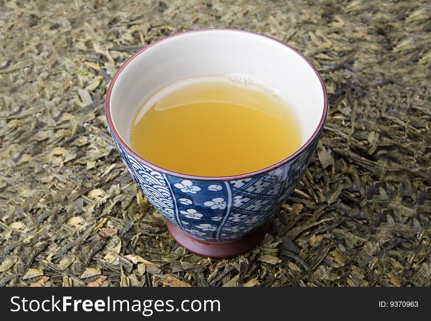 Full japanese tea cup sitting on fresh tea leaves. Full japanese tea cup sitting on fresh tea leaves