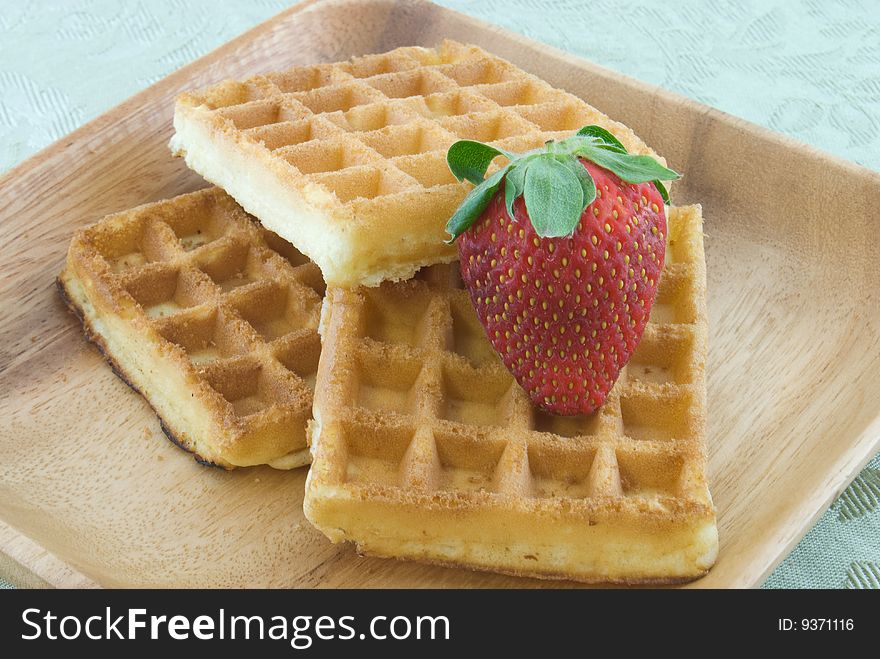 Three waffles stacked on plate with strawberry