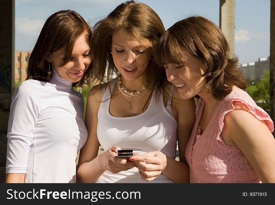 Portrait of three beautiful girls playing around with a mobile phone. Portrait of three beautiful girls playing around with a mobile phone