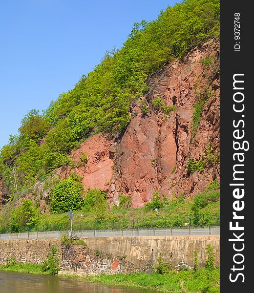 Mountain with trees along main road by river Weisse Elster.