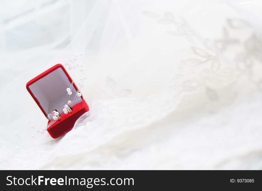 Red jewelry box with gold wedding rings on a white cloth