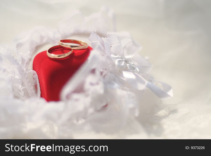 Gold wedding rings lying on a red jewelry box