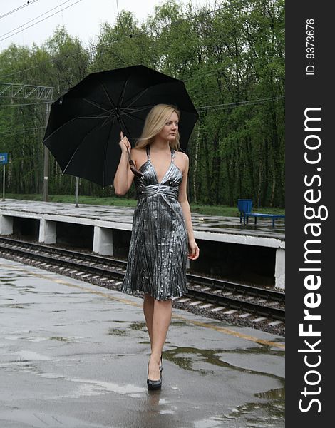 Girl walking with an umbrella on rairoad station