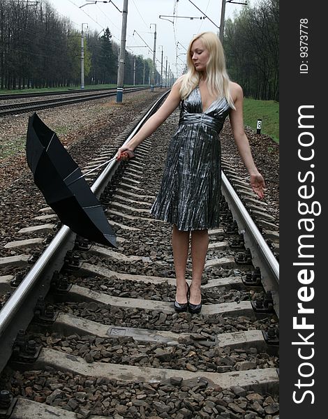 Girl with an umbrella standing on railroad