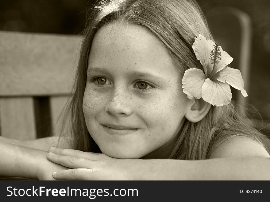 A white caucasian kid smiling with a flower in her hair picture in sepia tone. A white caucasian kid smiling with a flower in her hair picture in sepia tone