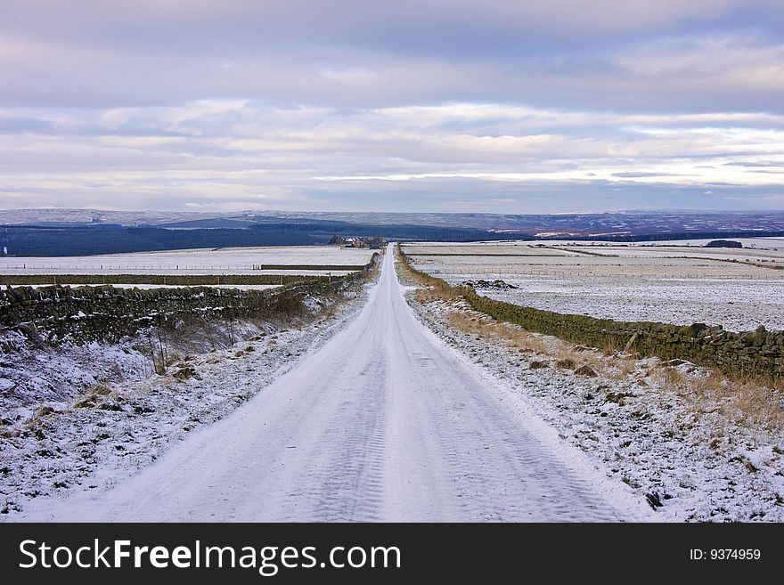 Deserted road across snow-covered moorland in the depths of winter. Deserted road across snow-covered moorland in the depths of winter