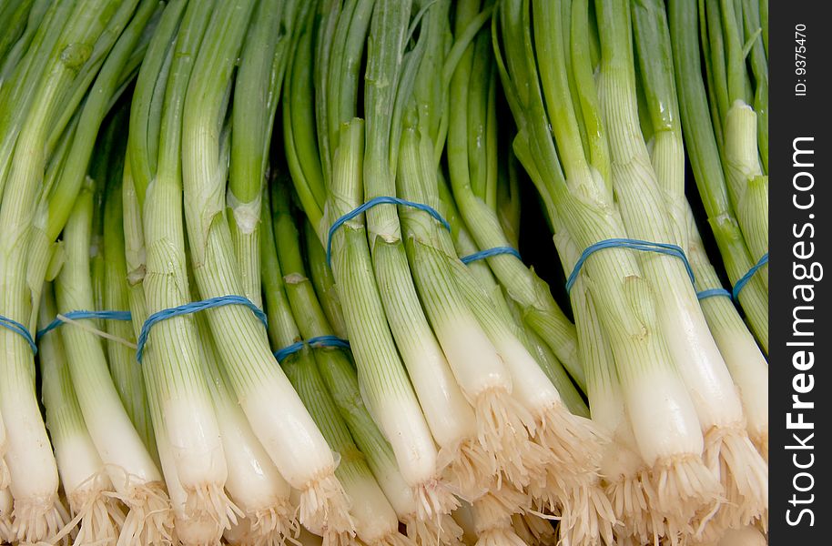 View of some scallions stacked for sale in a street market.