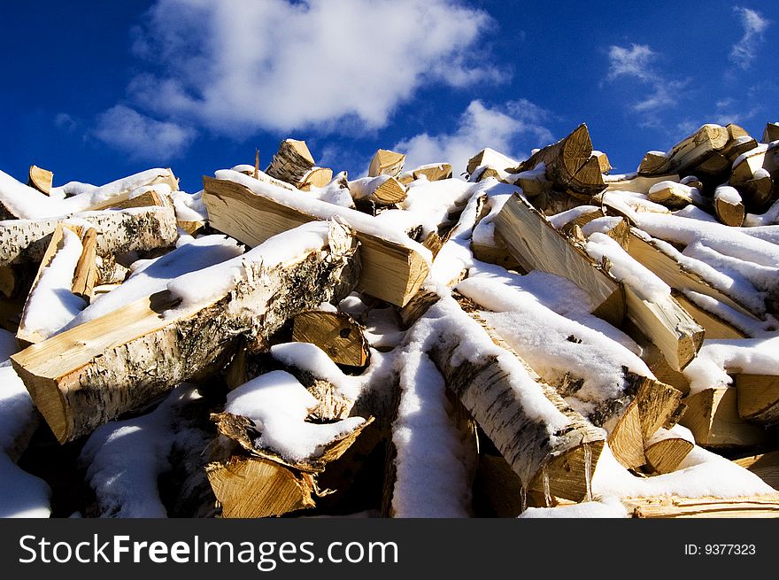 Huge heap of snow covered firewood with the sky on the background. Huge heap of snow covered firewood with the sky on the background.