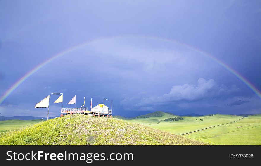A rainbow arched across the sky and grassland. A rainbow arched across the sky and grassland