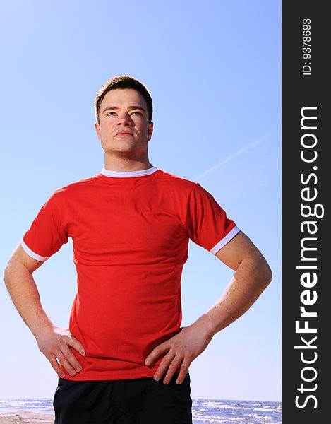 Young man standing at beach over the blue sky