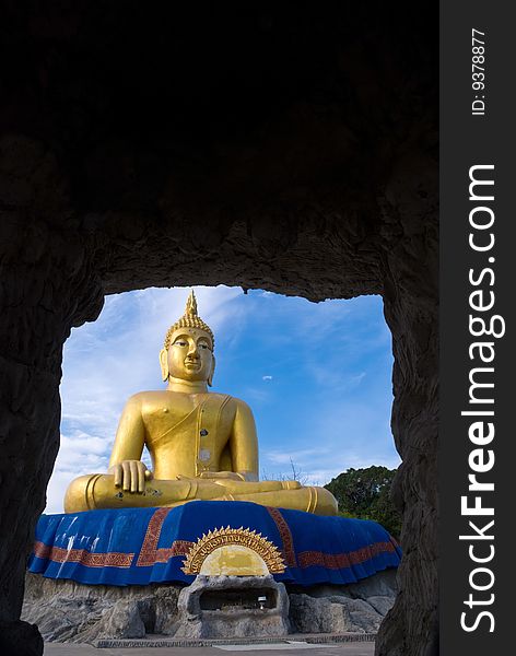 A large gold Buddha statue viewed from a cave. A large gold Buddha statue viewed from a cave