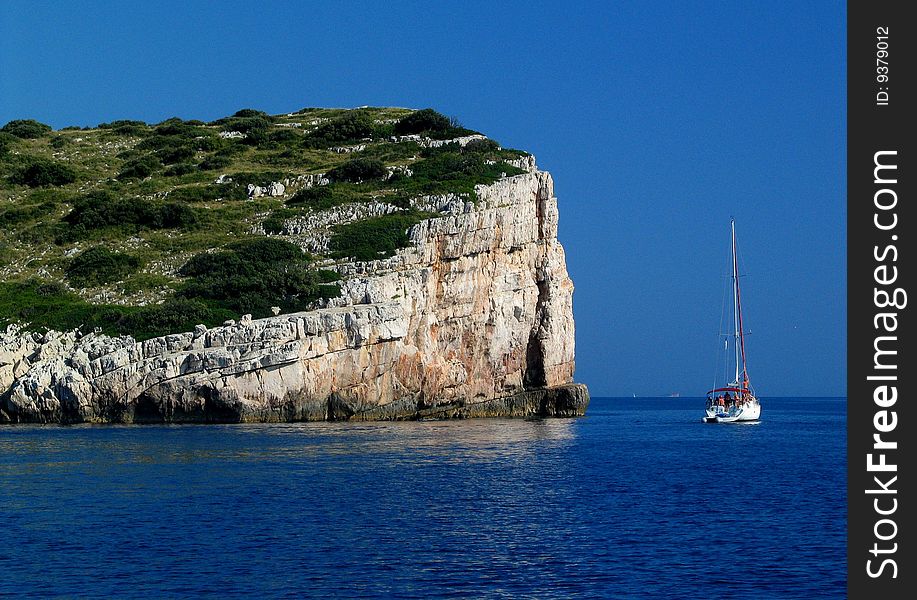 The yacht on calm sea near by rock. National park in Croatia.