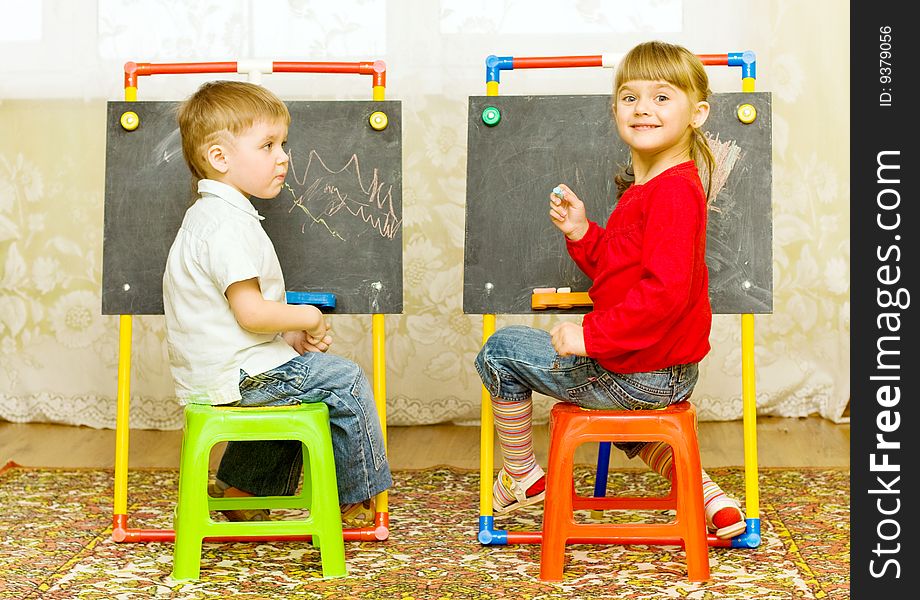 Girl and boy drawing on the blackboard with chalk