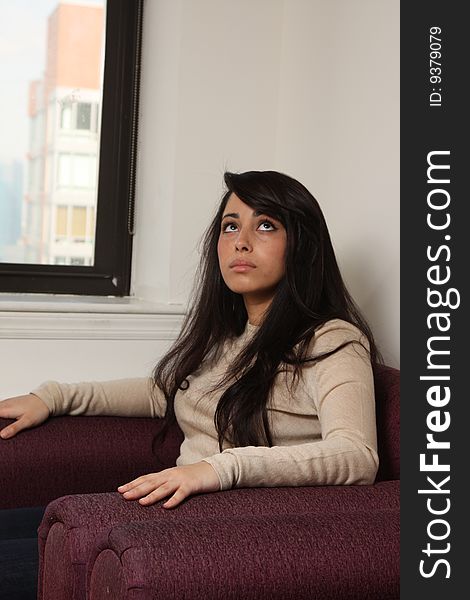 Young female sitting in arm chair, scared, looking up. Young female sitting in arm chair, scared, looking up