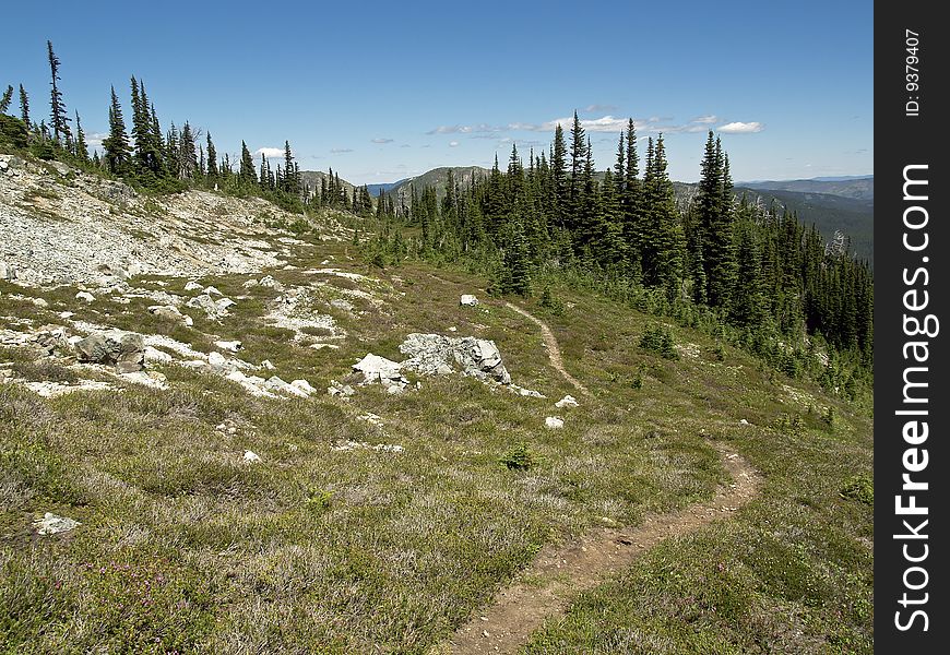 A faint trail winds it's way across a mountainside and over a ridge. A faint trail winds it's way across a mountainside and over a ridge