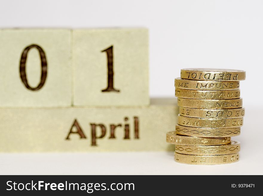 A close up photo of English one pound coins with the first of April showing in the background. A close up photo of English one pound coins with the first of April showing in the background