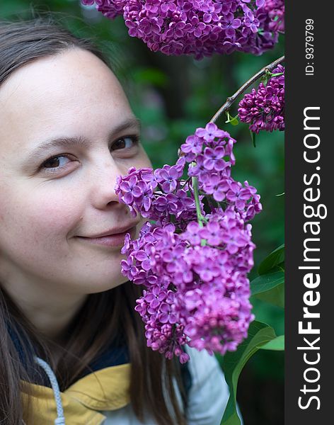 Young woman smelling the lilac flower and smiling. Young woman smelling the lilac flower and smiling