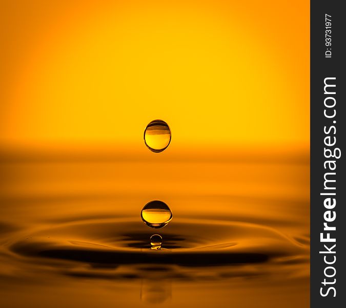 Drops of water falling in a pool in orange light. Drops of water falling in a pool in orange light.