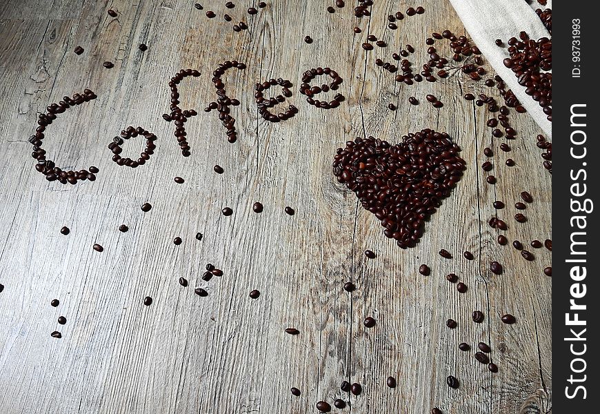 Coffee beans on a wood surface forming the word "coffee" and a heart shape.