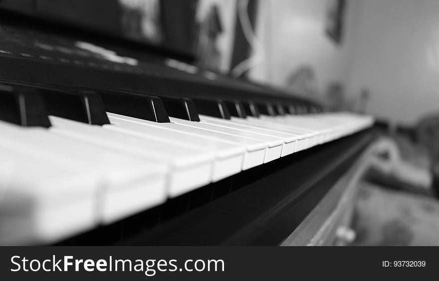 Close up of acoustic piano keys in black and white inside home.