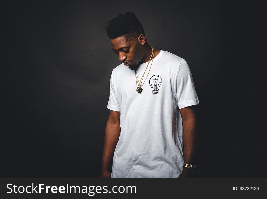 Studio portrait of young African American man wearing white t-shirt with light bulb and gold chains. Studio portrait of young African American man wearing white t-shirt with light bulb and gold chains.