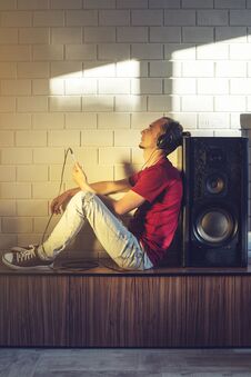 Handsome, A Music Lover Listens To Music With Headphones With A Mobile Phone On The Media And Large Speakers. Royalty Free Stock Photography