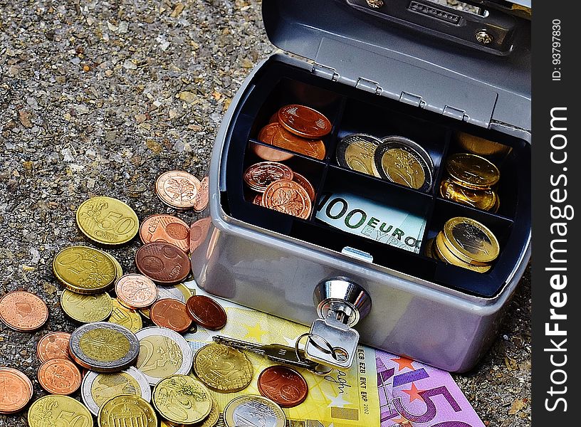 Close up of coins and banknotes for Euros in grey metal box on ground. Close up of coins and banknotes for Euros in grey metal box on ground.