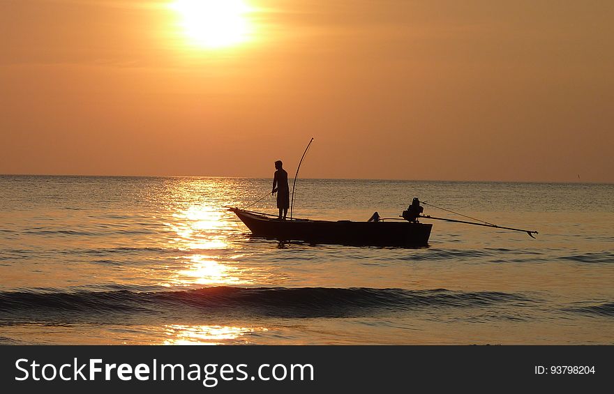 Fisherman in boat at sunset