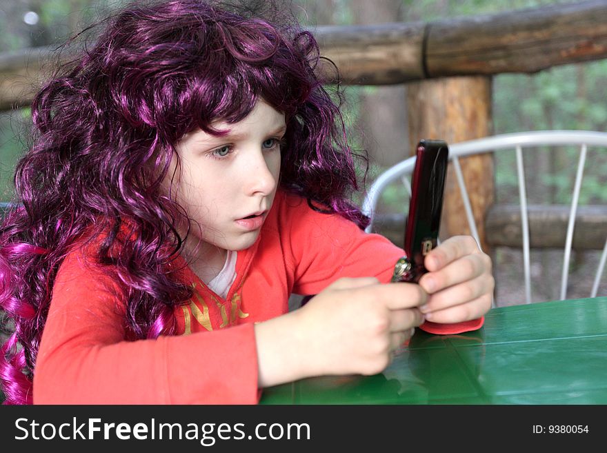 The girl plays by a mobile phone. The girl plays by a mobile phone