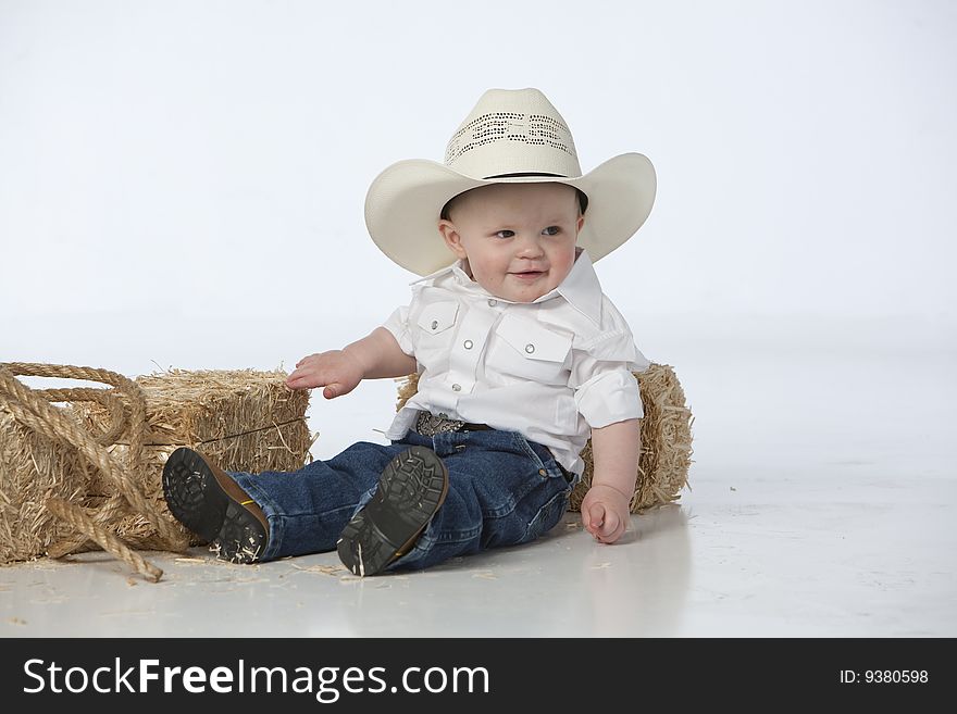 Little boy on white with cowboy hat on white background with hay bales and rope. Little boy on white with cowboy hat on white background with hay bales and rope