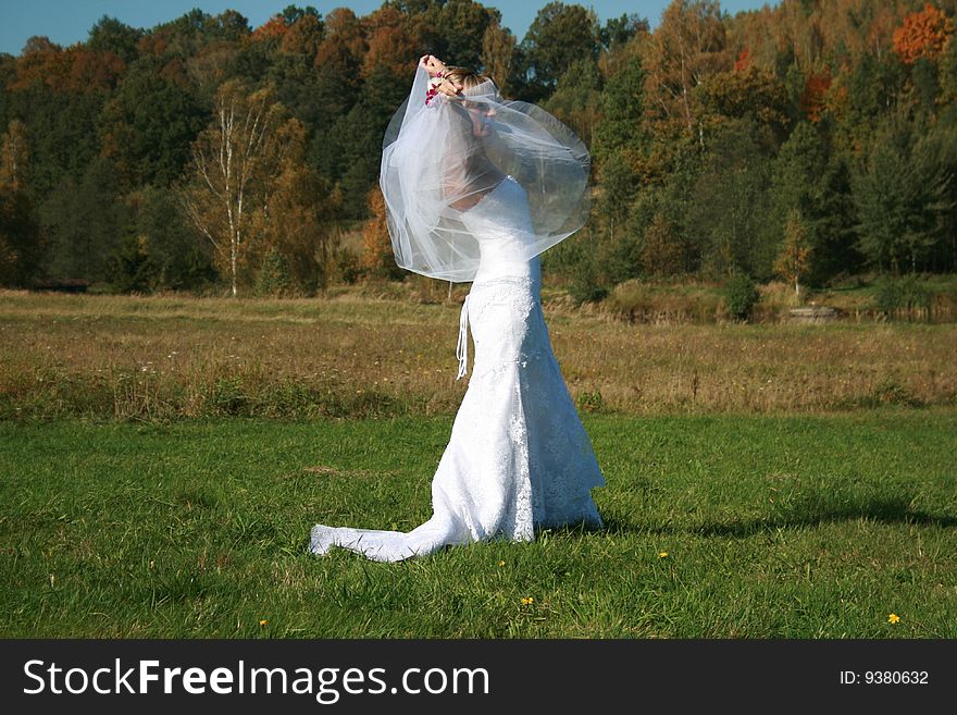 Bride With Bridal Veil Flying On A Meadow