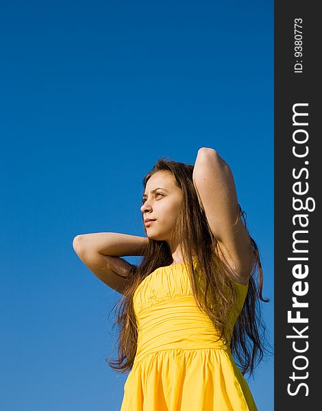 A young girl in yellow dress looking to the sky