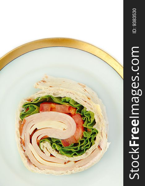 Turkey wrap sandwich with tomato cheese and lettuce. Viewed from above on a plate.