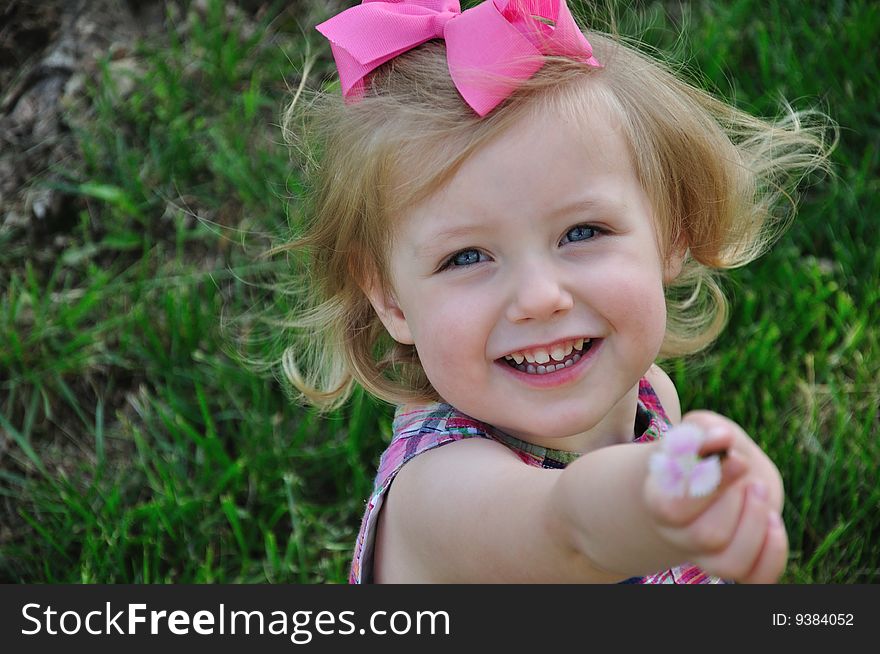 A young smiling girl showing off a freshly picked flower. A young smiling girl showing off a freshly picked flower