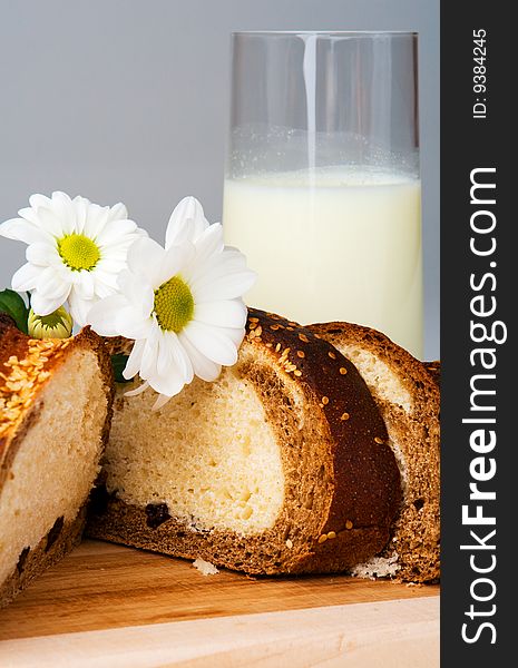 Sliced bread, milk and flowers on gray. Sliced bread, milk and flowers on gray