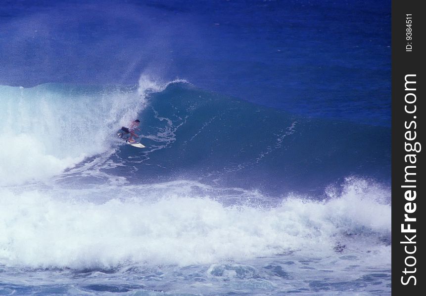 Surfer getting tubed on Oahu with offshore winds blowing the wave mist. Surfer getting tubed on Oahu with offshore winds blowing the wave mist.