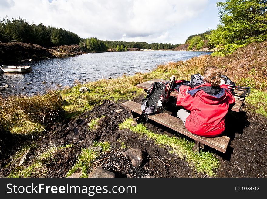 Woman relaxing by lake in remote loch in scotland