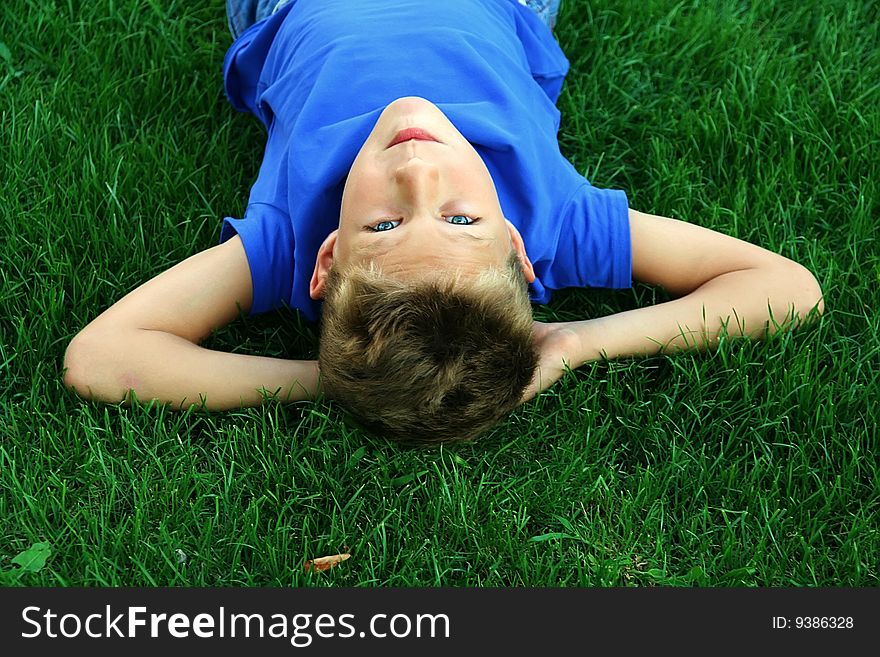 Cute blond boy on the green grass