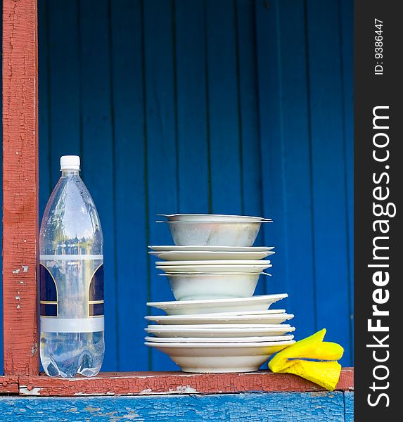 Plates and bottle of water on a wooden shelf. Plates and bottle of water on a wooden shelf