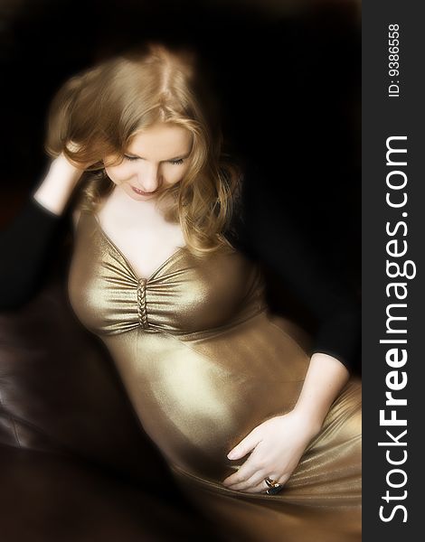 Beautiful pregnant woman in gold dress with blond hair. Beautiful pregnant woman in gold dress with blond hair